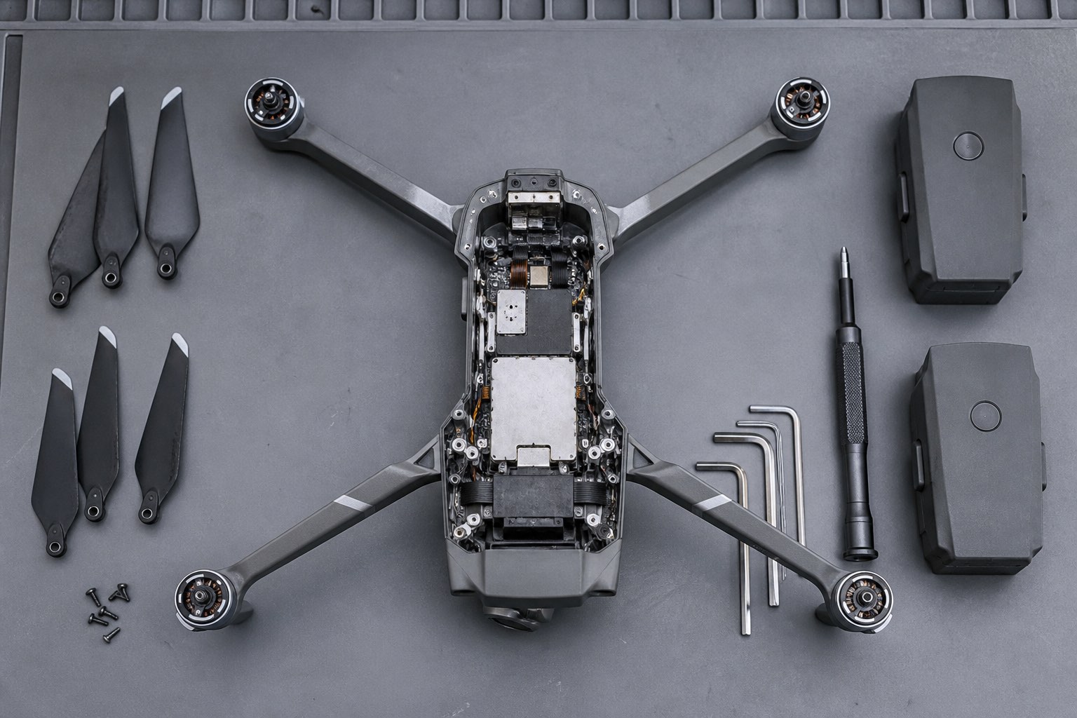 Tezgâh üzerinde sökülmüş drone gövdesi, pervaneler ve bataryalar